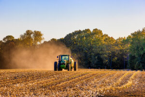A tractor driving through a dry field.