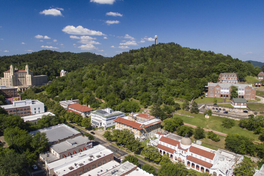 A drone shot of downtown Hot Springs, featuring Bath House row, a row of bohemian-style buildings on a busy street.