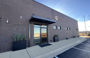 A rectangular brick building with glass double doors and a gold Veralux logo