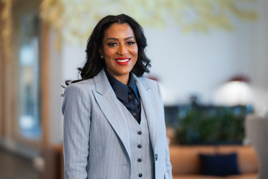 Latriece Watkins, African American woman in a gray suit in front of a blurred office background.