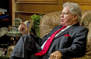 John Allison, an older white man in a suit, sits in a leather armchair in an office.