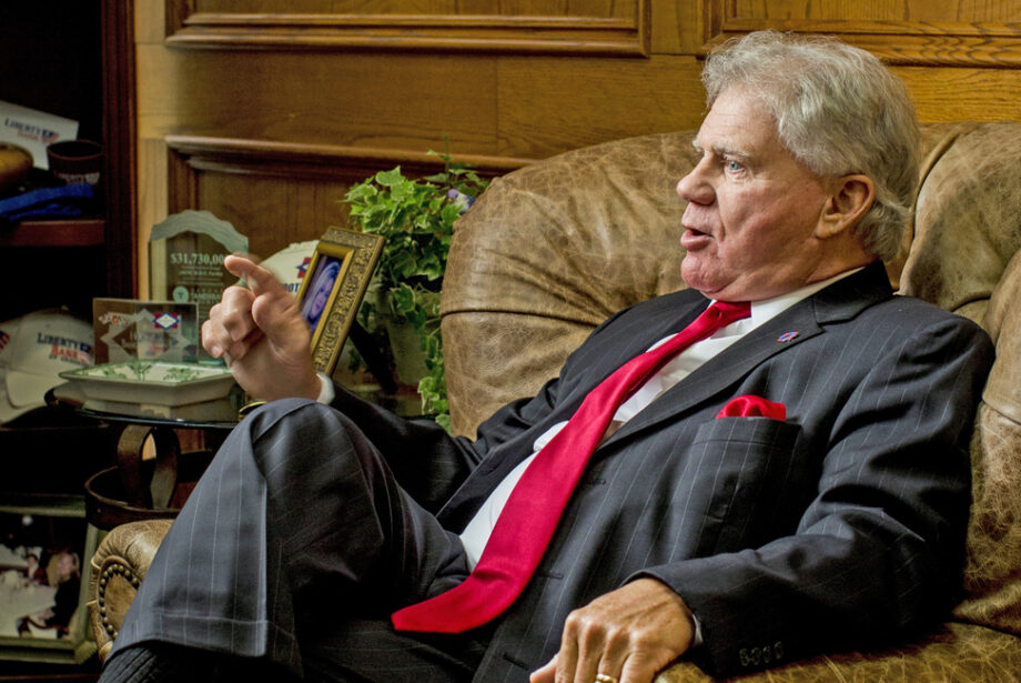 John Allison, an older white man in a suit, sits in a leather armchair in an office.