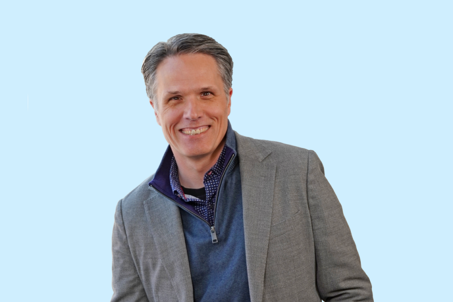 Chris East, Principal Architect at Cromwell Architects Engineers of Little Rock. A middle-aged man in a gray blazer and blue shirt on a light blue background.