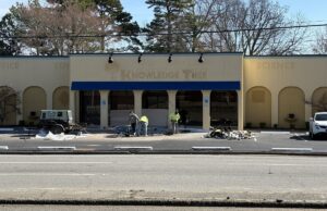 A street view of an empty yellow building with decorative arches and blue accents.