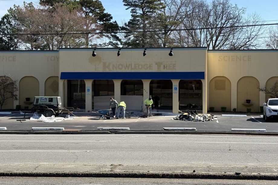 A street view of an empty yellow building with decorative arches and blue accents.