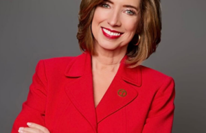 KATV meteorologist Melinda Mayo stands smiling with arms crossed, wearing a red blazer and a KATV Channel 7 pin