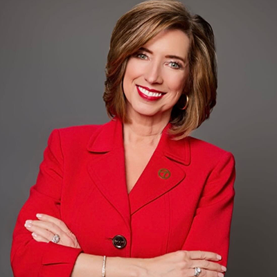KATV meteorologist Melinda Mayo stands smiling with arms crossed, wearing a red blazer and a KATV Channel 7 pin