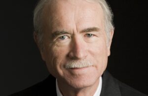 A business headshot of Greg Roberts, a retired architect, in a suit and tie