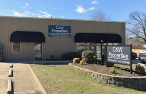 A street view of C&W Properties, a singles-story building with black window shades.