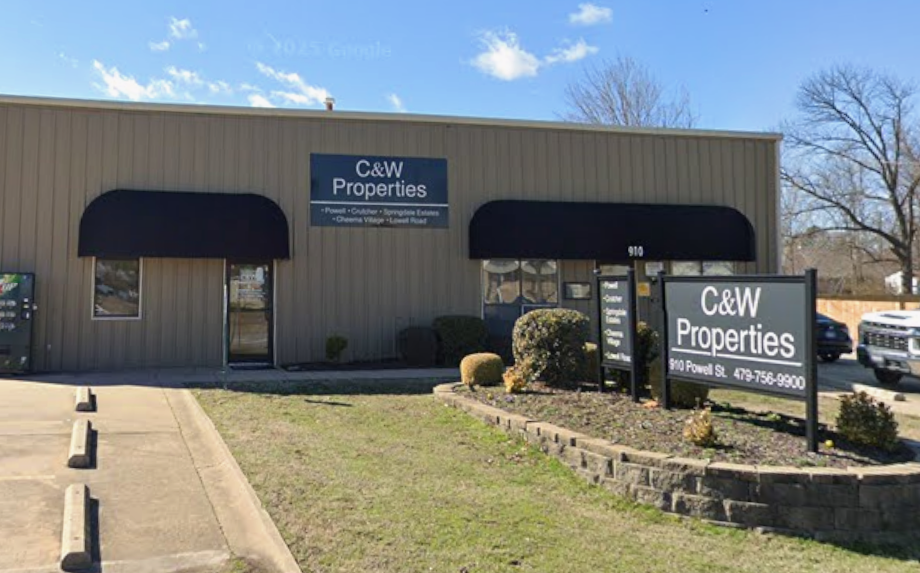A street view of C&W Properties, a singles-story building with black window shades.