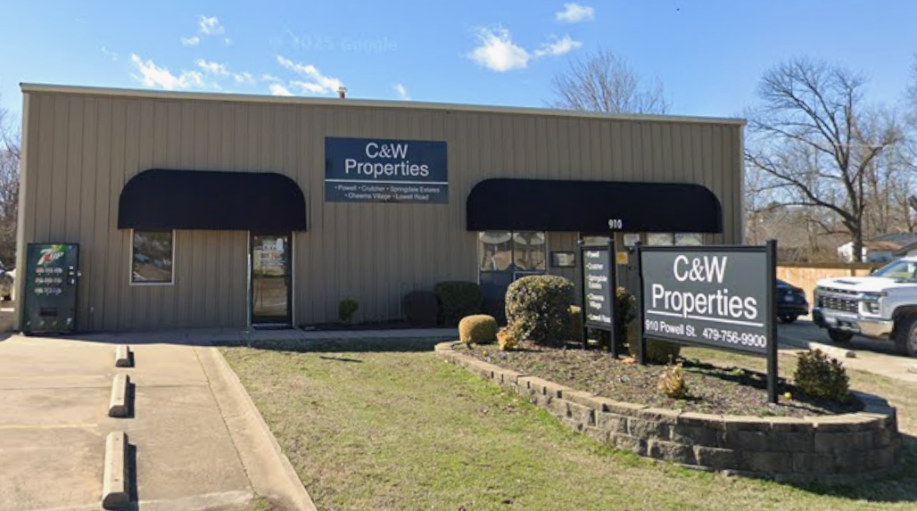 A street view of C&W Properties, a singles-story building with black window shades.