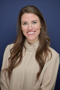 Lauren Waldrip, a young white woman with long brown hair in a cream colored sweater. 