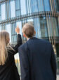 Three business people examining a high-rise building from the street.