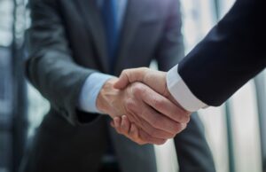 A close up of two men in suits shaking hands.