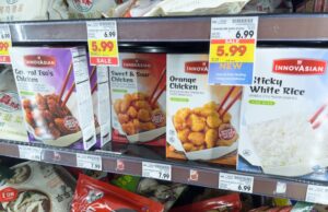Packages of InnovAsian chicken and white rice on display on the shelf of a grocery store with price tags below each product