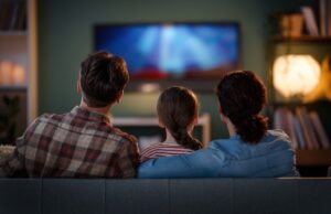 A father, mother and daughter sitting on their sofa watching TV