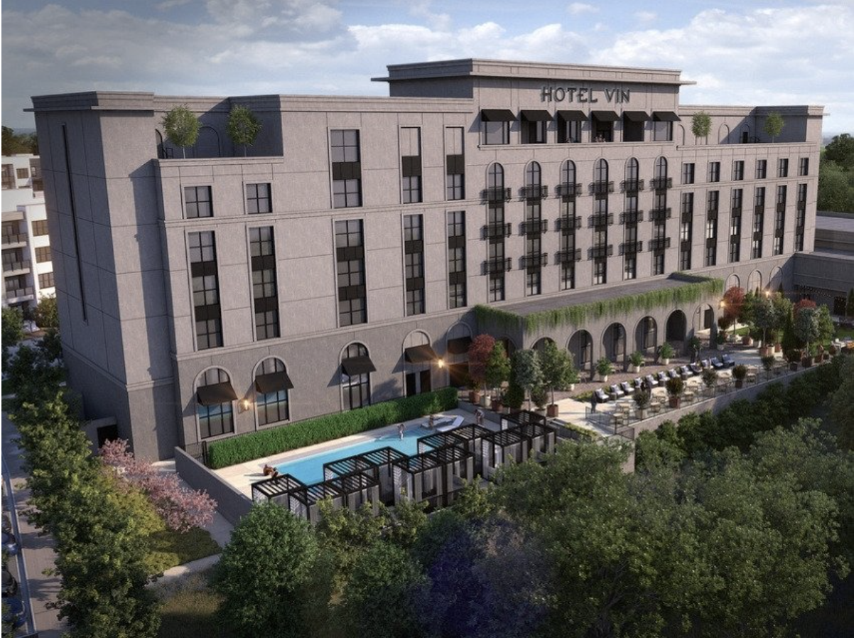 A multi-story brown brick hotel with a pool and greenery