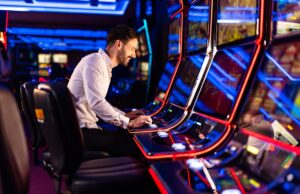 A man sitting at a row of slot machines in a casino.